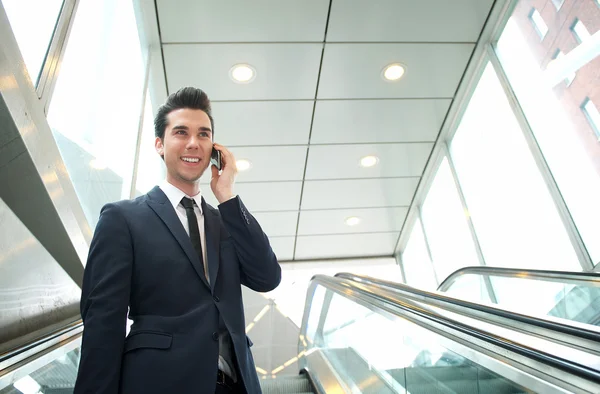 Uomo d'affari che parla al telefono sulla scala mobile — Foto Stock