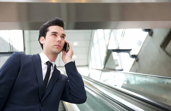 Viajando hombre de negocios hablando por teléfono en escaleras mecánicas — Foto de Stock