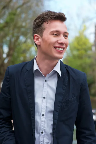 Jeune homme confiant en veste bleue, souriant à l'extérieur — Photo