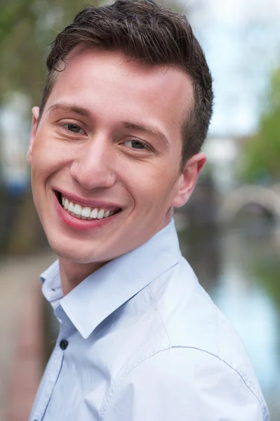 Retrato de un joven atractivo sonriendo al aire libre — Foto de Stock