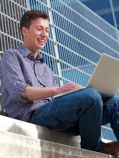 Joven hombre sonriendo a la computadora portátil al aire libre — Foto de Stock