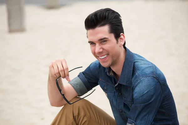 Happy young man sitting outdoors — Stock Photo, Image