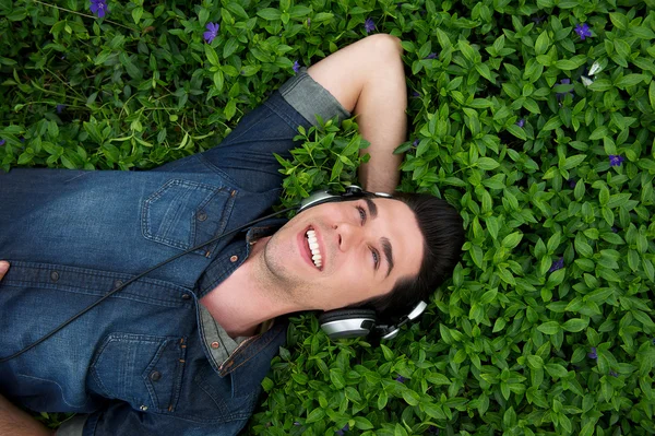 Young man relaxing with headphones outdoors - from above — Stock Photo, Image