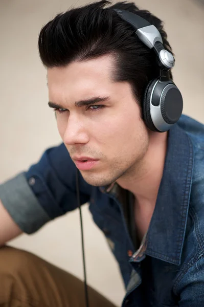 Привабливий чоловік слухає музику на навушниках на відкритому повітрі — стокове фото