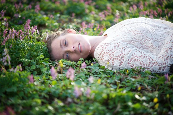 Beautiful young lady lying on grass and flowers — Stock Photo, Image