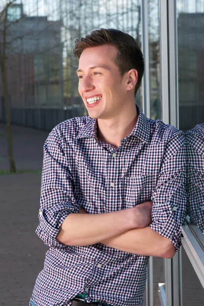 Glücklicher junger Mann, der mit verschränkten Armen im Freien steht — Stockfoto