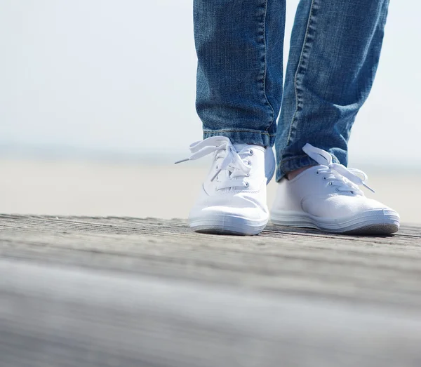 Woman standing outdoors in blue jeans and comfortable white shoes — Stock Photo, Image