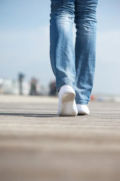 Porträtt av en kvinna som går i blå jeans och bekväma vita skor — Stockfoto