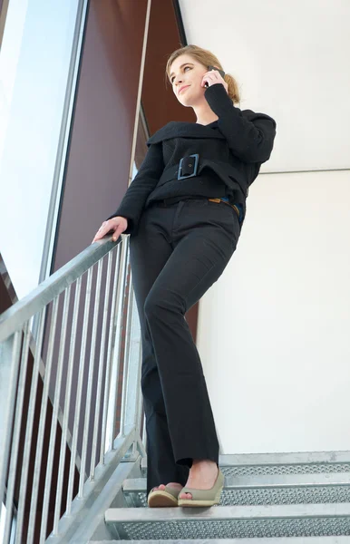 Mujer de negocios de pie en las escaleras y hablando por teléfono — Foto de Stock