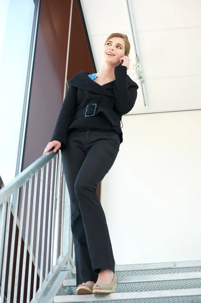 Business woman standing on stairs and talking on mobile phone — Stock Photo, Image