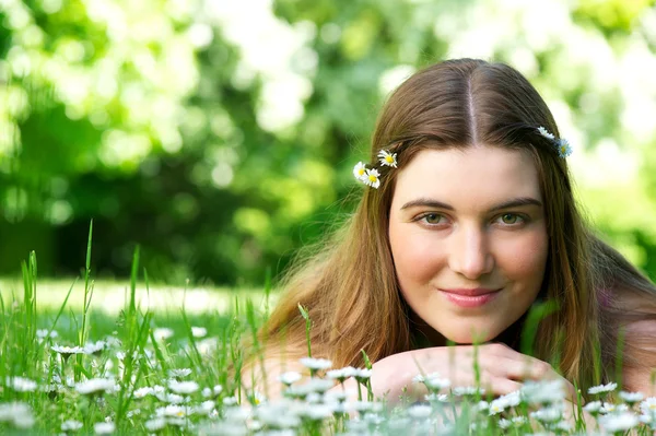 Junge Frau liegt mit Blumen auf Wiese — Stockfoto