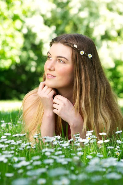 Portrait of a beautiful young woman lying on green grass outdoors — Stock Photo, Image