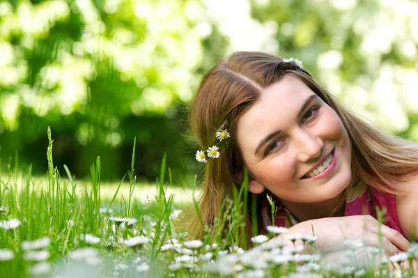 Schöne junge Frau, die draußen mit Blumen lächelt — Stockfoto