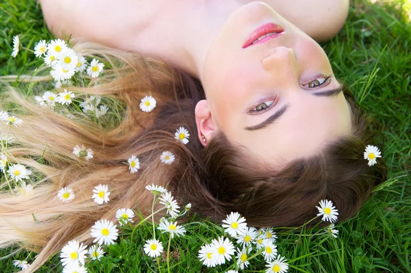 Mujer joven acostada sobre hierba y flores al aire libre — Foto de Stock