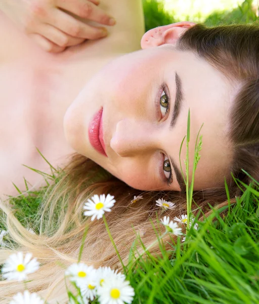 Jonge vrouw liggend op groen gras buitenshuis — Stockfoto