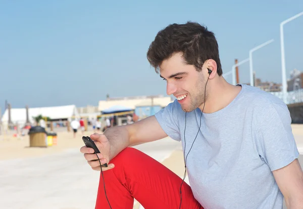 Портрет красивого молодого человека, слушающего mp3 плеер на открытом воздухе — стоковое фото
