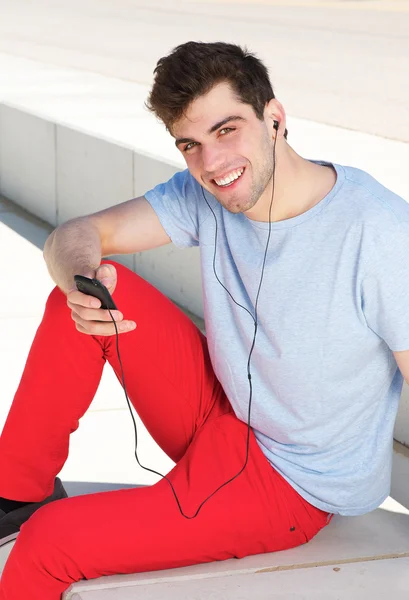 Fiatal ember mosolyogva és hallgató-hoz zene, mp3-lejátszó — Stock Fotó