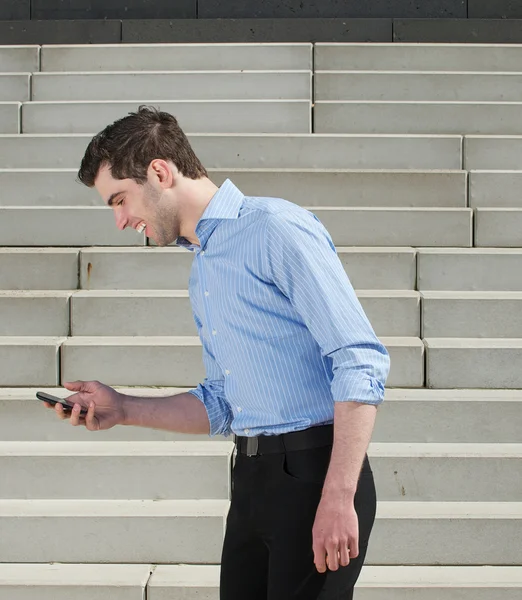 Giovane uomo che cammina all'aperto e guardando il telefono cellulare — Foto Stock