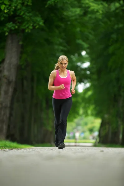 Aktive junge Frau joggt im Park — Stockfoto