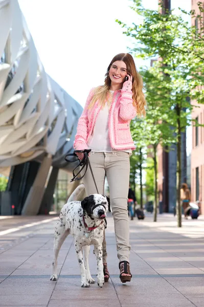 Female walking her dog outdoors and talking on mobile phone — Stock Photo, Image