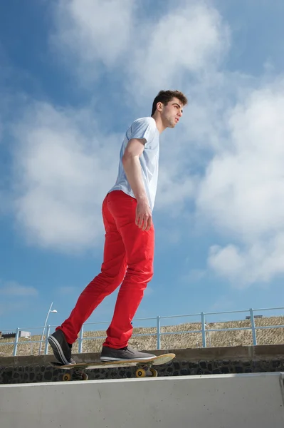 年轻男子滑板与蓝蓝的天空背景 — 图库照片
