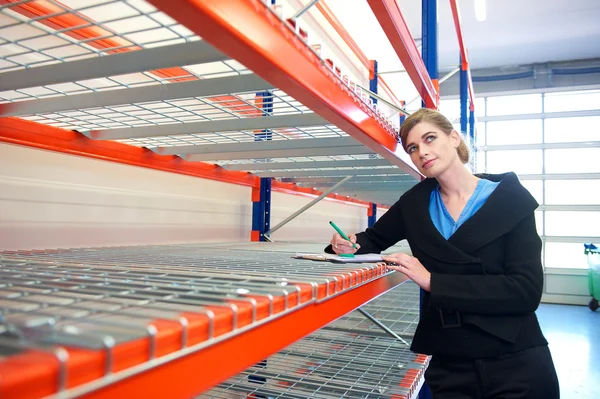 Businesswoman writing on clipboard in warehouse — Stock Photo, Image