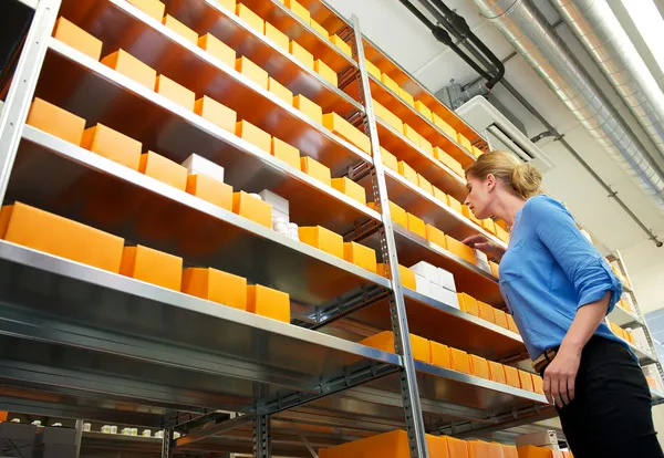 Feminino farmácia empregado procurando prateleiras para medicamentos e medicamentos — Fotografia de Stock