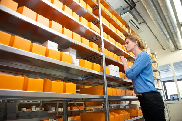 Female pharmacy worker looking for medicine in warehouse — Stock Photo, Image