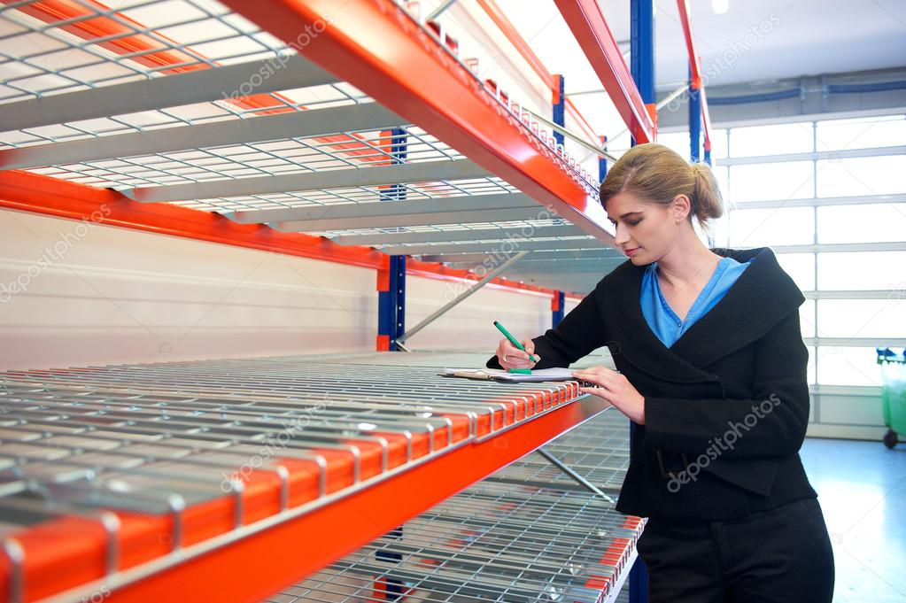 Young business woman writing on clipboard in warehouse