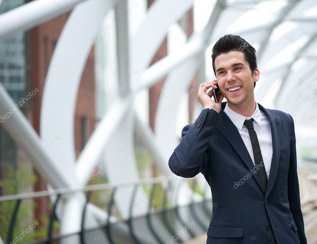 Smiling business man talking on mobile phone in the city