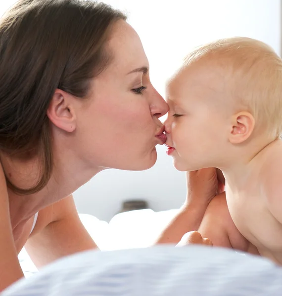 Beautiful woman kissing baby — Stock Photo, Image