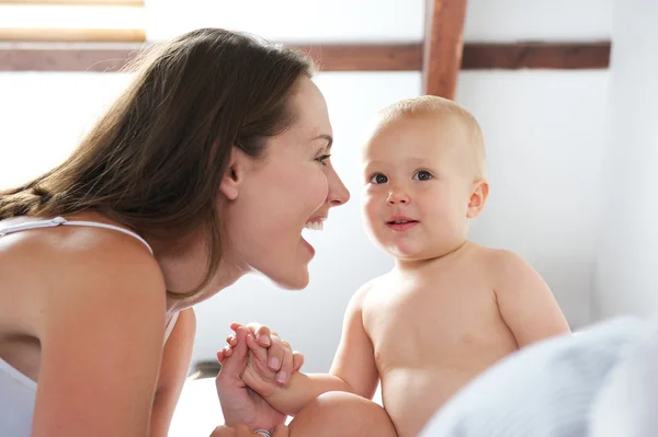 Mère heureuse jouant avec bébé au lit — Photo