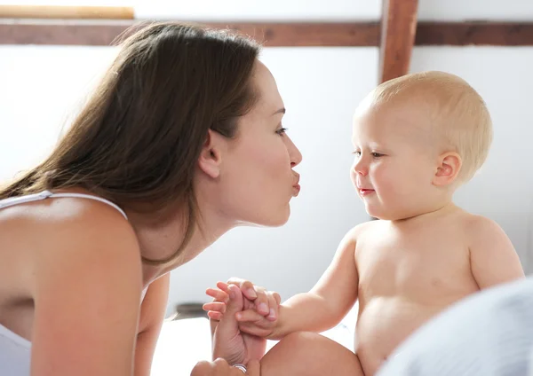 Mor och söt baby spelar på sängen — Stockfoto