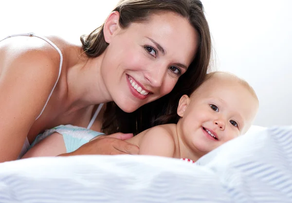 Mãe e bebê sorrindo na cama — Fotografia de Stock