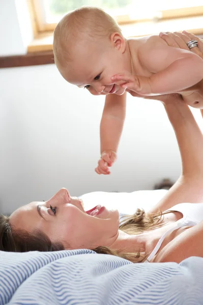 Mulher e bebê brincando na cama — Fotografia de Stock