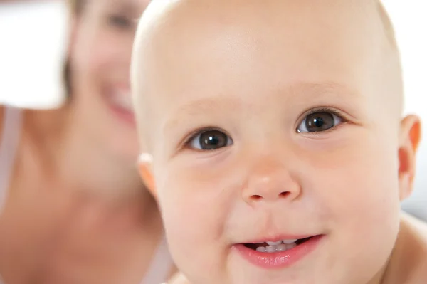 Baby leende med mamma i bakgrunden — Stockfoto