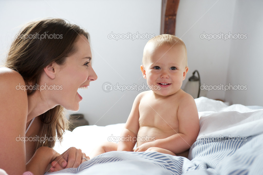 Portrait of mother and baby smiling on bed