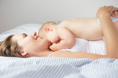 Baby hugging mother in bed