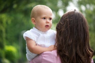 omzunun üzerinden açık havada tutarak bebek anne