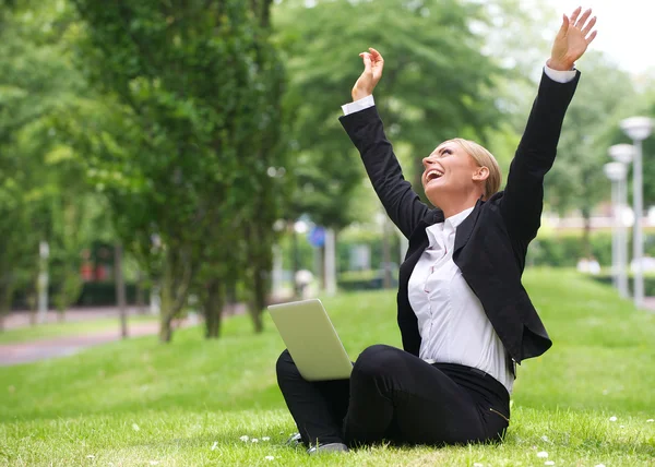 Succesvolle zakenvrouw met laptop en uitgestrekte armen — Stockfoto