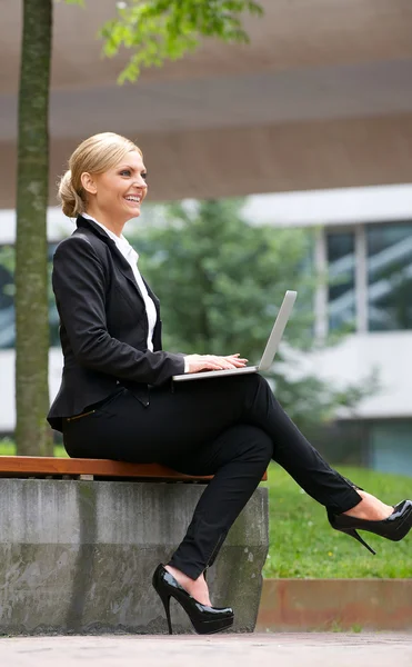 Empresária sorrindo e trabalhando ao ar livre no laptop — Fotografia de Stock