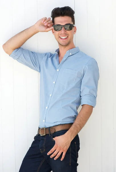 Knap jonge man die lacht met zonnebril buitenshuis — Stockfoto