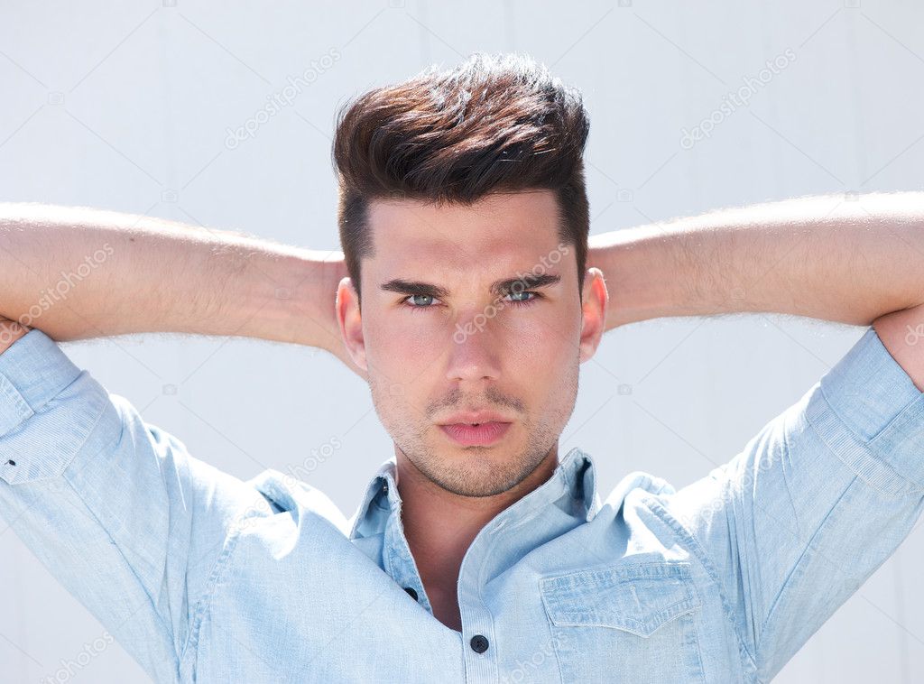 Attractive male fashion model with hands behind head