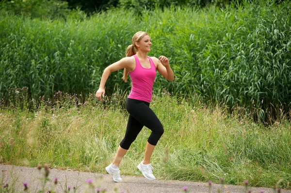 Schöne junge Frau joggt im Park — Stockfoto