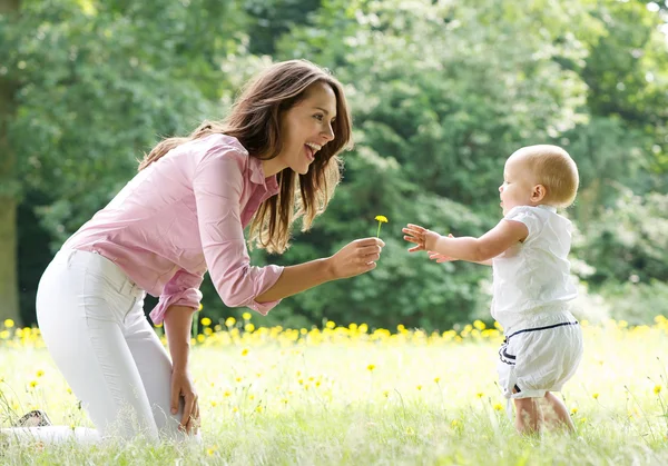 Madre feliz enseñando al bebé a caminar en el parque — Foto de Stock