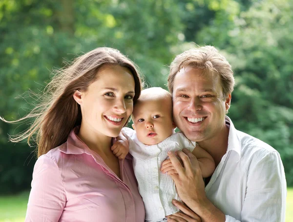 Retrato de uma jovem família feliz sorrindo com bebê — Fotografia de Stock