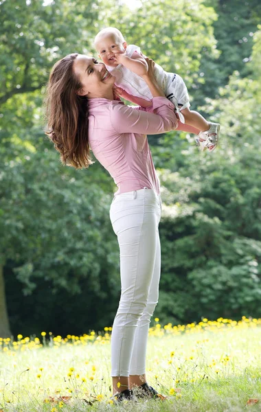 Mulher bonita segurando bebê no parque — Fotografia de Stock