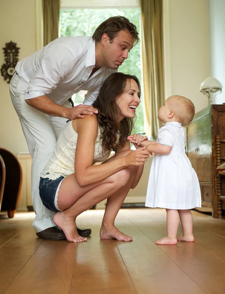 Lycklig familj leende på baby stående hemma — Stockfoto