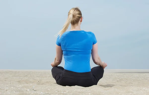 Potret seorang wanita duduk di pasir dalam pose yoga — Stok Foto