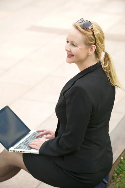 Gelukkig zakenvrouw buiten zitten met laptop — Stockfoto